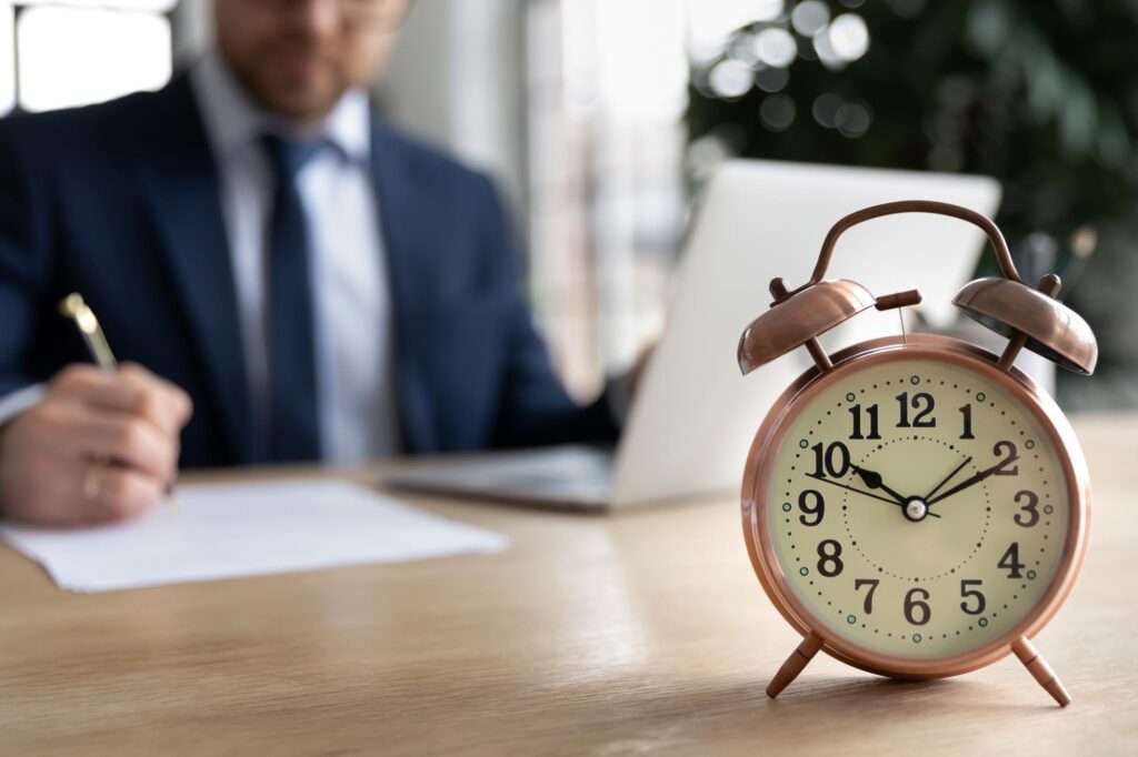 Close Up Alarm Clock On Desk, Businessman Working On Background