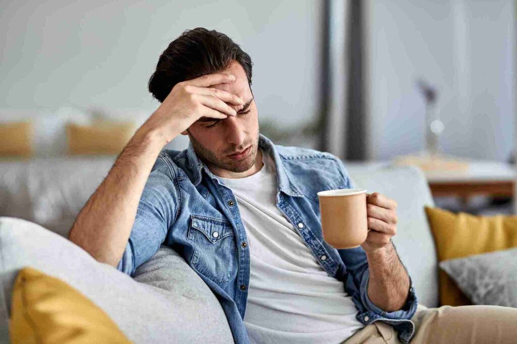 Young Distraught Man Drinking Coffee Thinking Something While Sitting Sofa 11zon