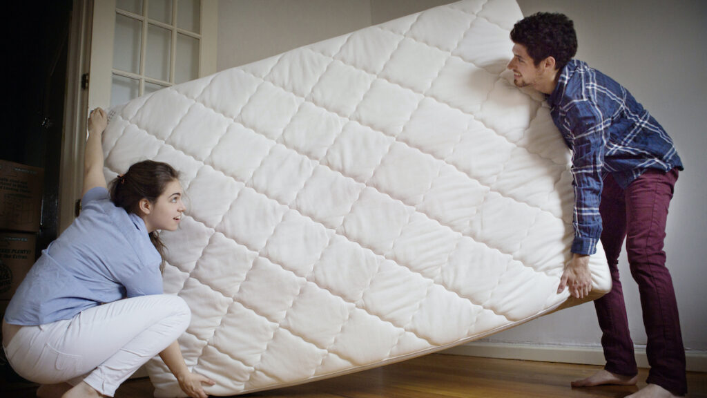 Couple Carrying Mattress In Room