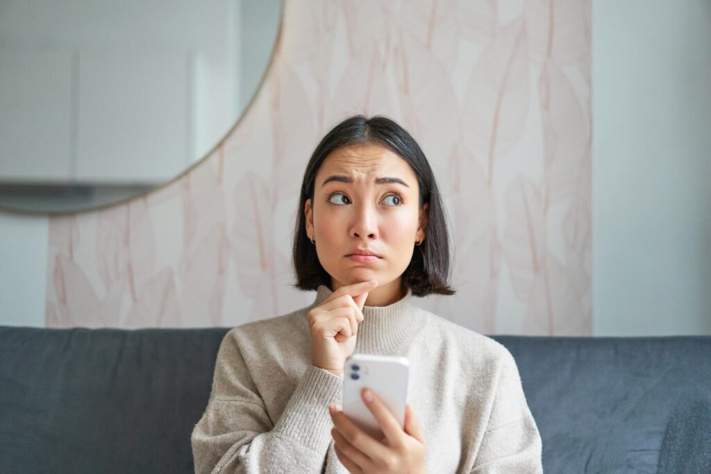 Portrait Girl Sitting Sofa With Smartphone Looking Thoughtful Hesitant Mobile Phone Scr 1258 148349
