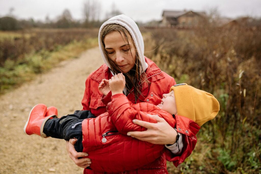A woman lovingly holds a child on a rural path, depicting warmth and togetherness.