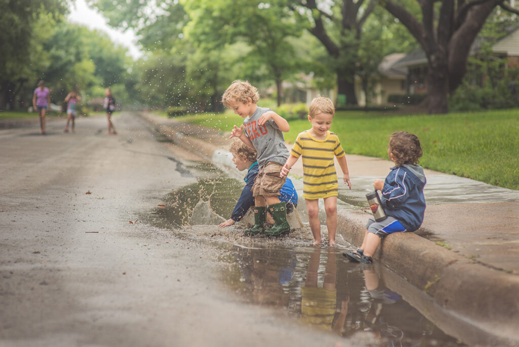 Kids Playing In A Water Puddle By Angela Ross