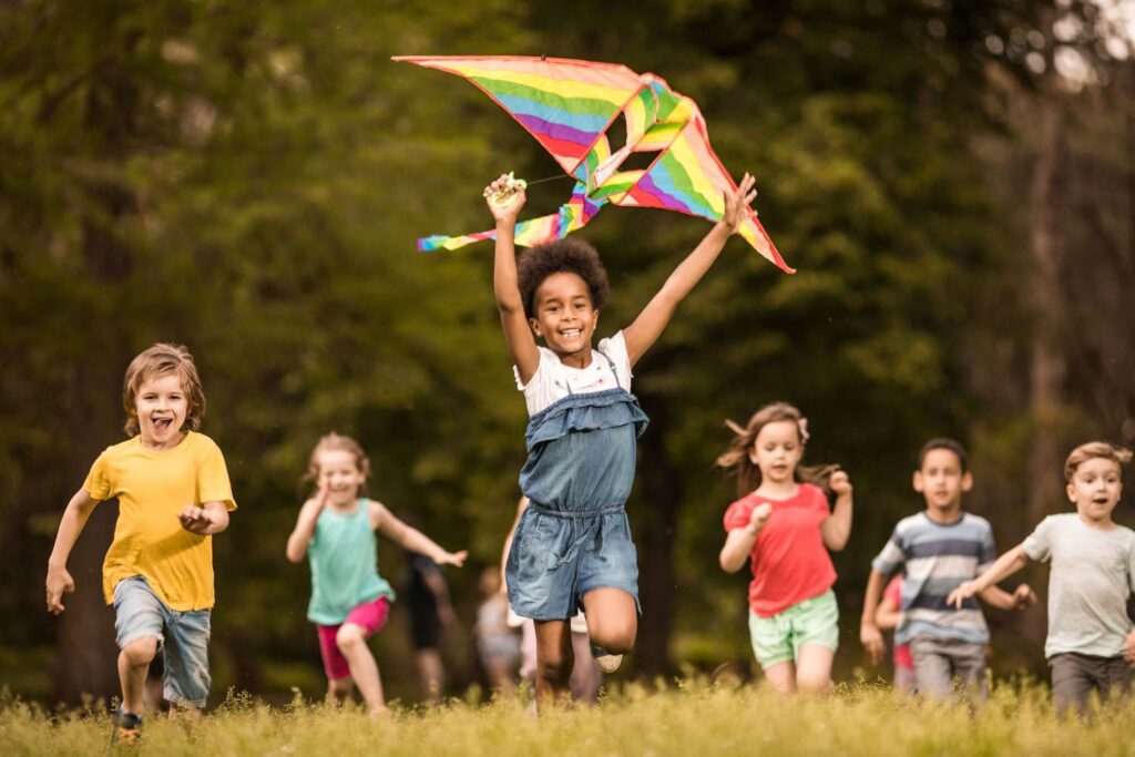 Large Group Of Joyful Kids Running With A Kite In Springtime 1185810377 Dcb01232039742648e6c978b22d94991
