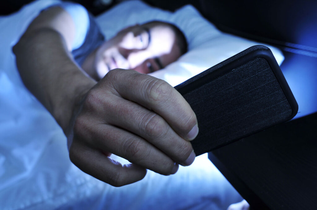 37559875 Closeup Of A Young Man In Bed Looking At The Smartphone At Night