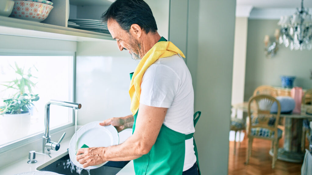 Middle,age,man,with,beard,smiling,happy,washing,dishes,at