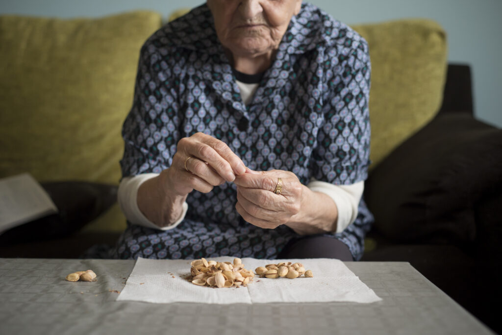 Aged Woman Eating Pistachios At Home