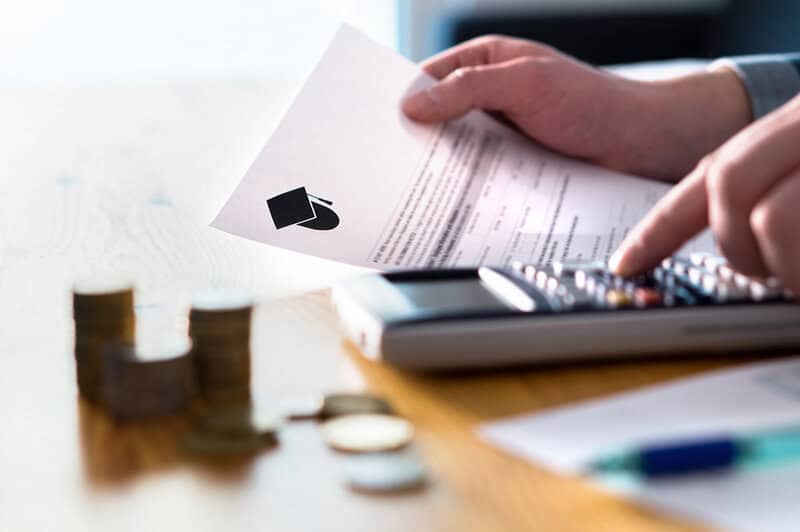 Man Counting College Savings Fund, Tuition Fee Or Student Loan With Calculator. Education Price And Expenses Concept. Money And Papers On Table.