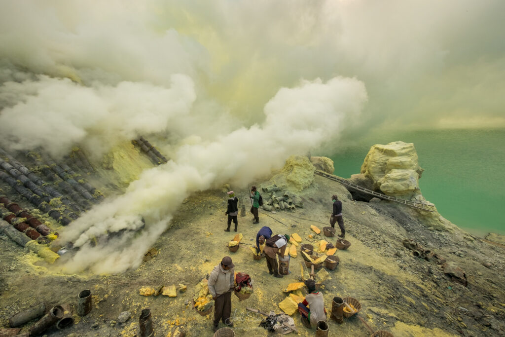 Miner Working And Breaking Sulphur Blocks, Surrounded By Fumes A