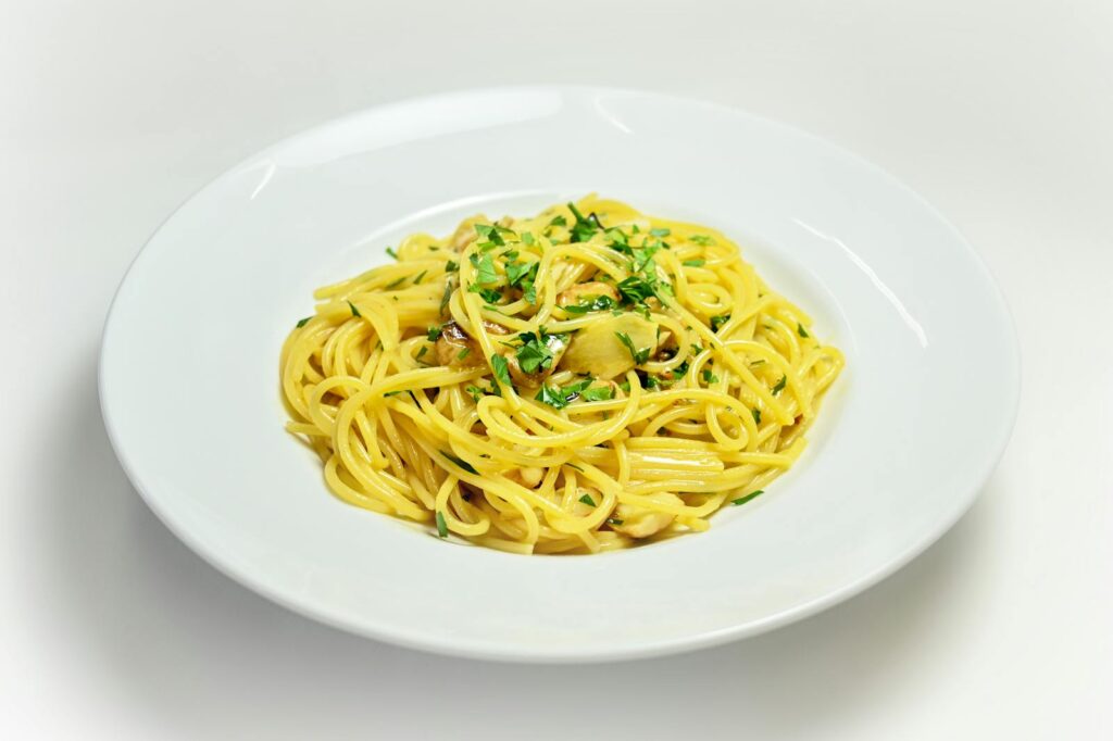 Close-up of a plate of classic Italian spaghetti aglio e olio garnished with fresh herbs.