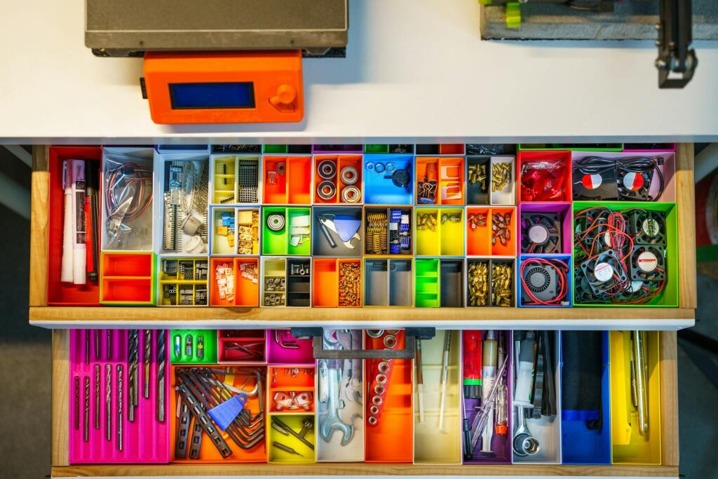 Top view of a colorful and organized workshop drawer filled with tools and electronic components.
