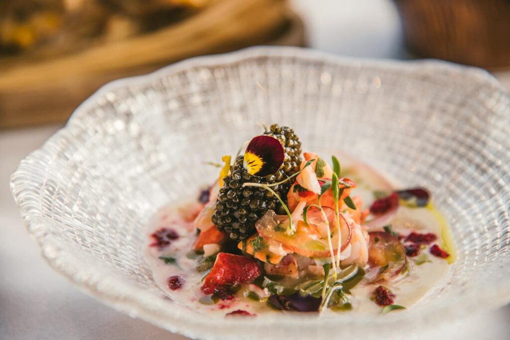 Elegant seafood dish with caviar served in a glass bowl, showcasing vibrant colors and textures.