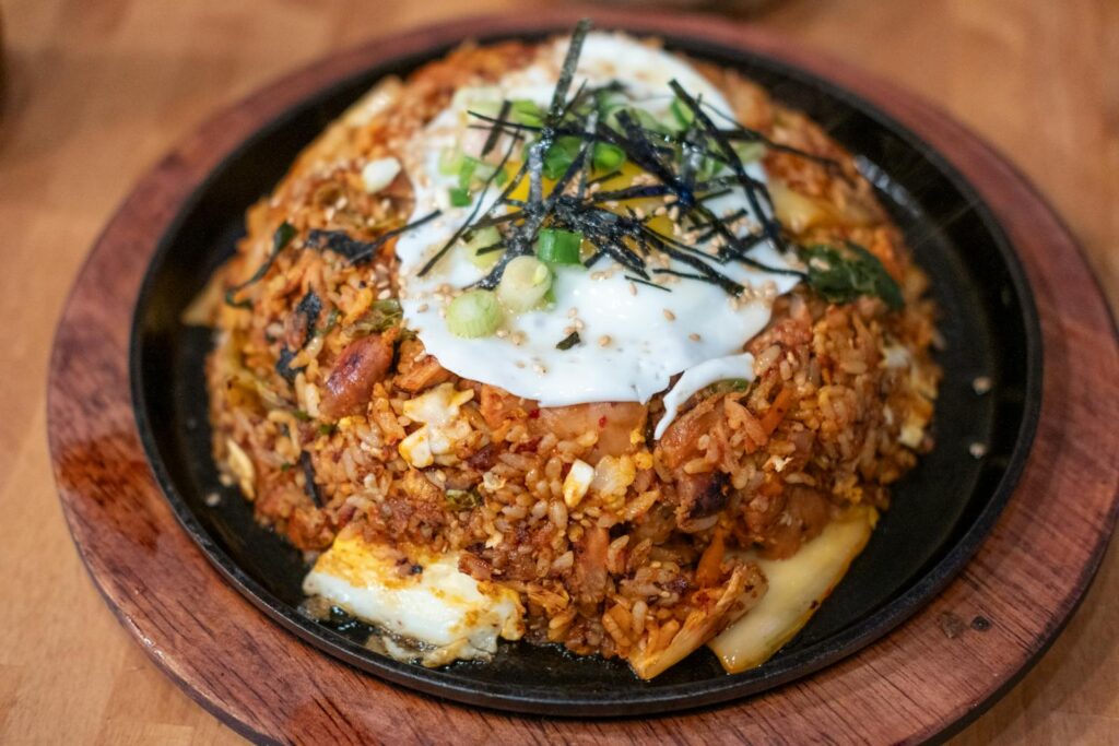 Delicious Korean fried rice topped with egg, seaweed, and scallions for a savory meal.