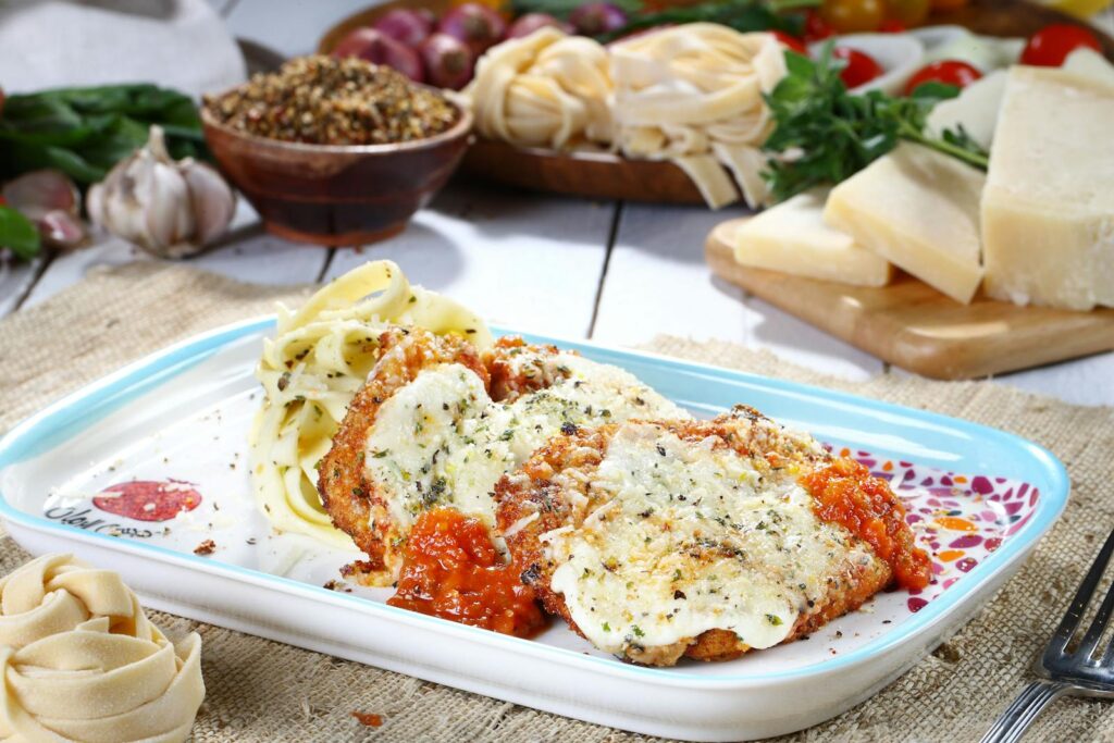 Tasty chicken parmesan with pasta and fresh ingredients on a rustic table.