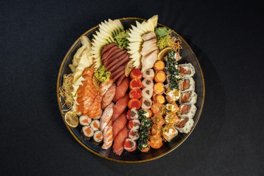 Aerial view of a diverse sushi platter featuring salmon, tuna, avocado, and vibrant garnishes.