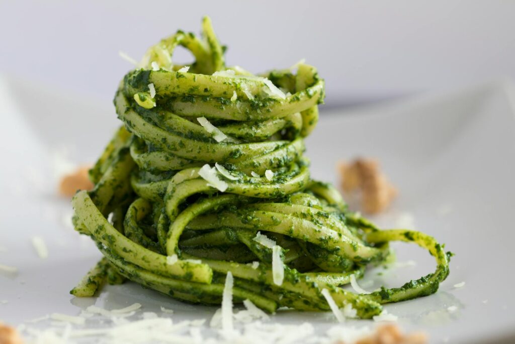 Close-up of delicious pesto pasta, beautifully plated with parmesan shavings.