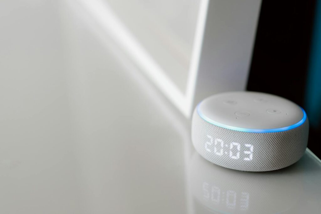 Close-up of a smart speaker with a digital clock display on a minimalist surface.