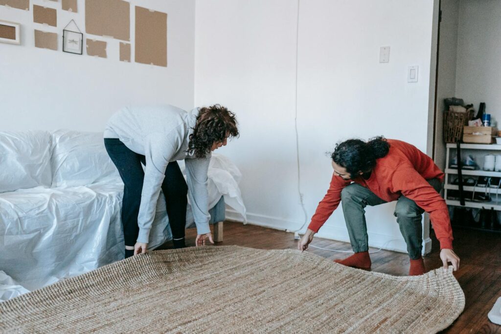 Couple arranging a rug in their contemporary apartment living room, teamwork concept.