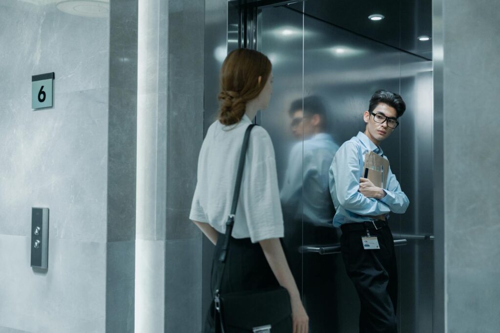 Office colleagues meeting in an elevator, showcasing a professional setting.