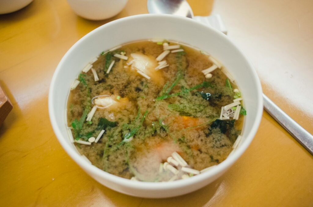 Close-up of appetizing miso soup with fresh ingredients in a white bowl.