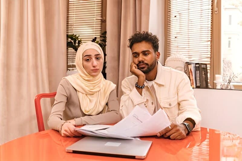 A worried couple reviewing documents at their kitchen table