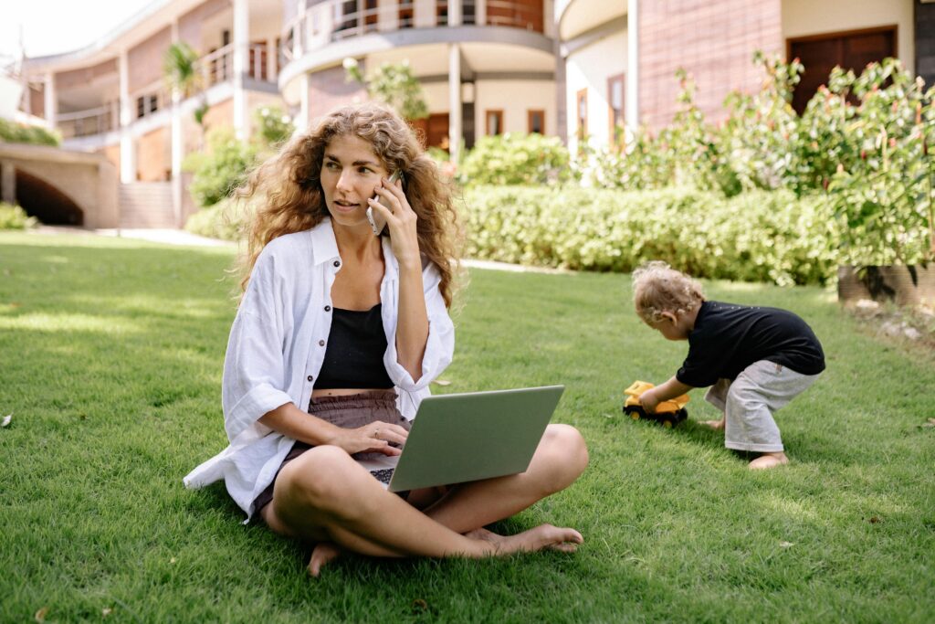 Child sits outdoors holding an outdated laptop