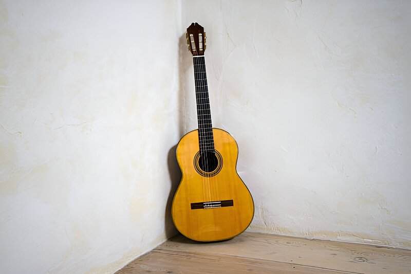 Dusty guitar leans forgotten in the corner