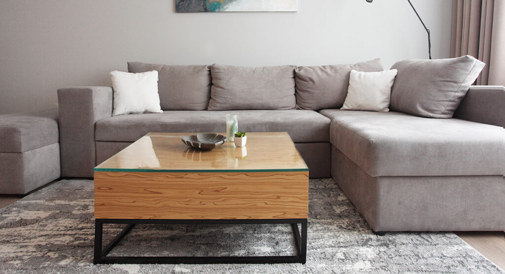 Grey Corner Couch With Three Pillows Standing In Bright Living Room Interior With Painting And Carpet.lightning Off