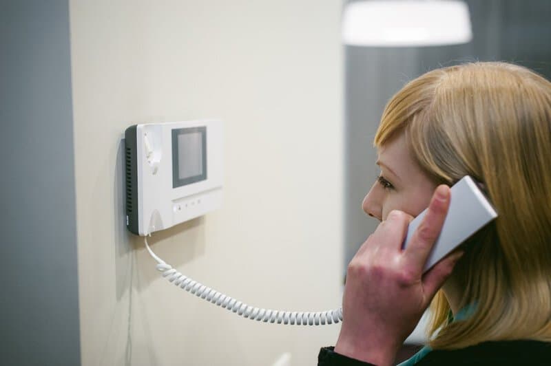 Blonde,woman,answers,the,intercom,call,while,holding,the,phone