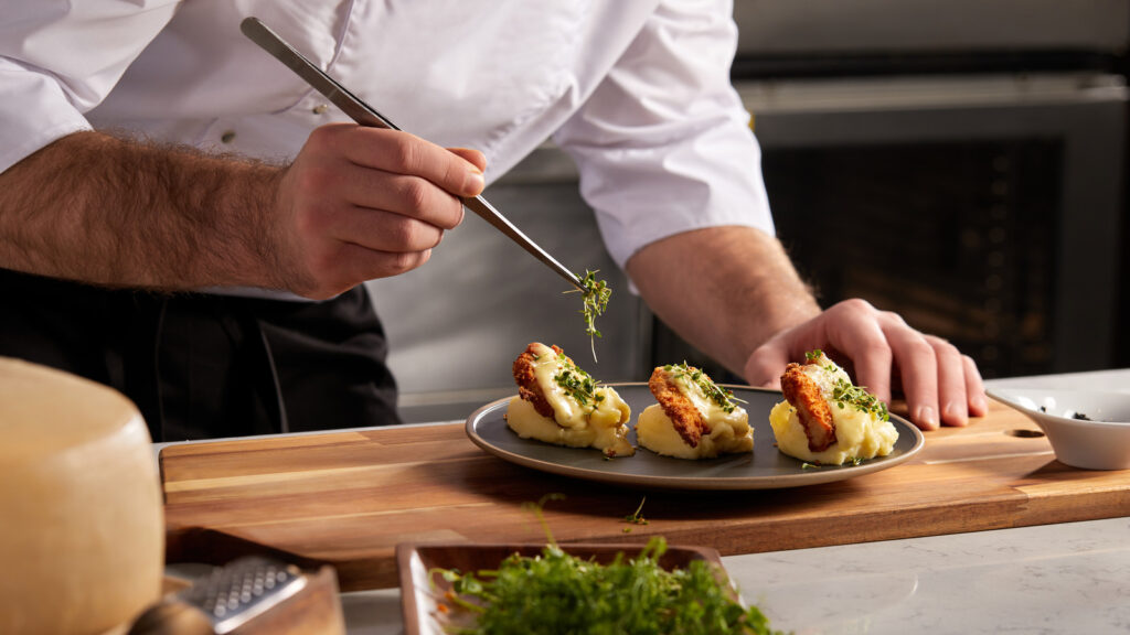 Cropped,photo,close Up,hands,of,male,cook,adding,greens,finishing