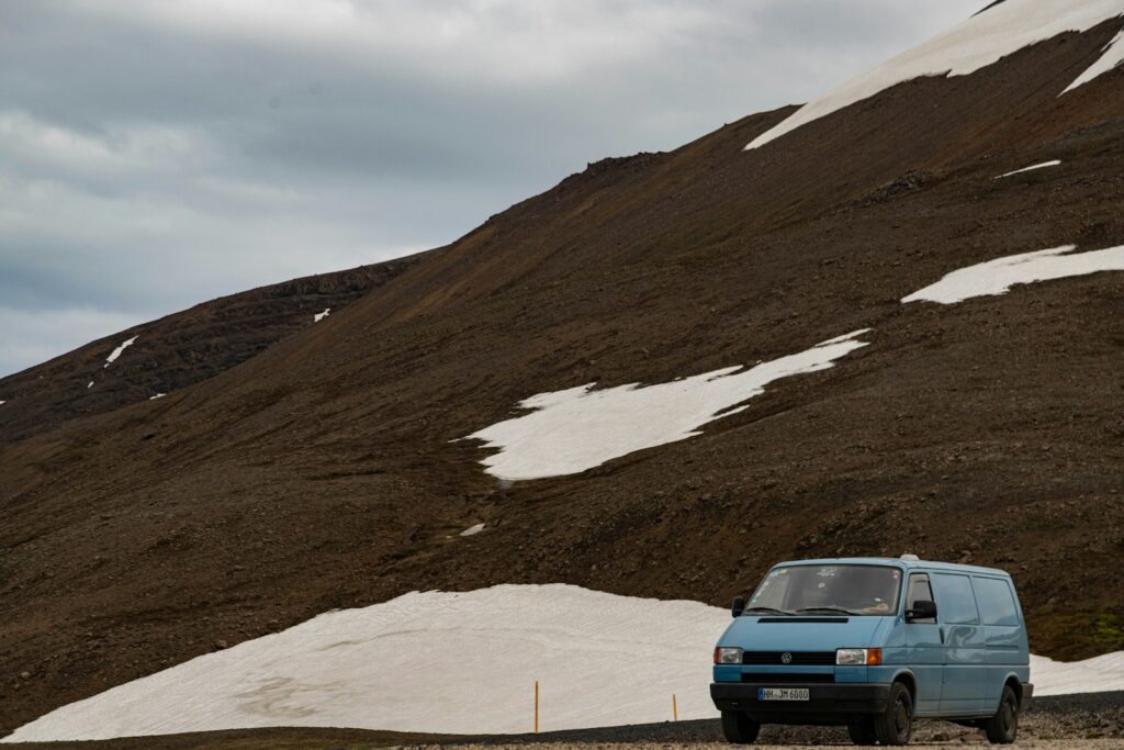 a blue van is parked in front of a mountain