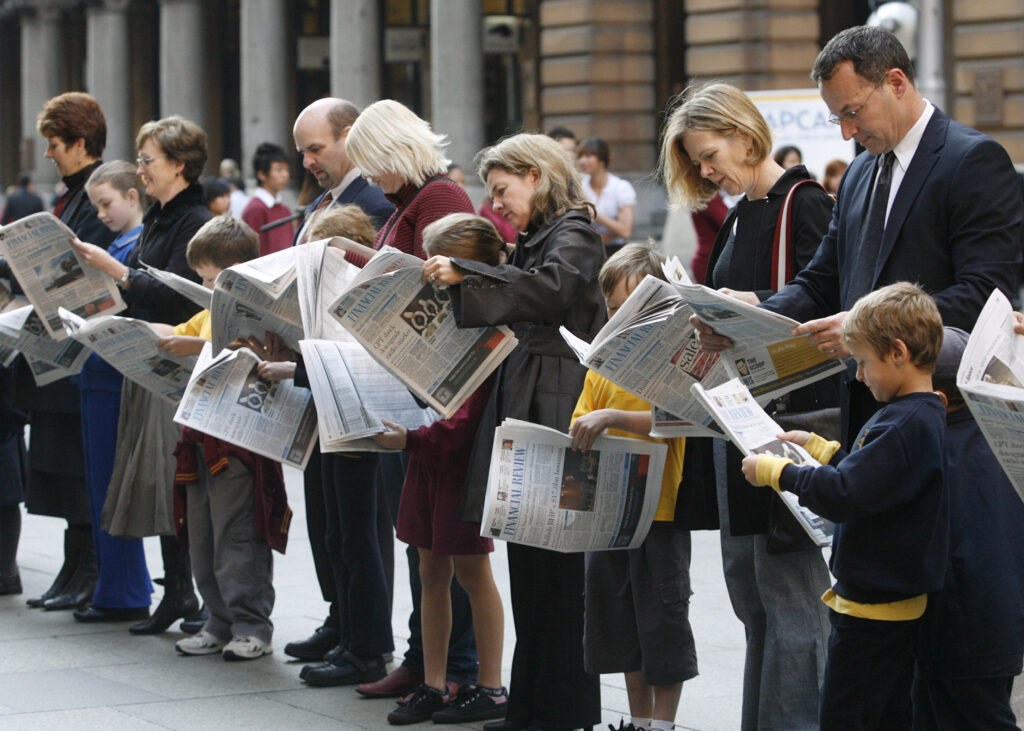 Children, Mimicking The Actions Of Adults Standing With Them, Read Newspapers At Martin Place In Central Sydney