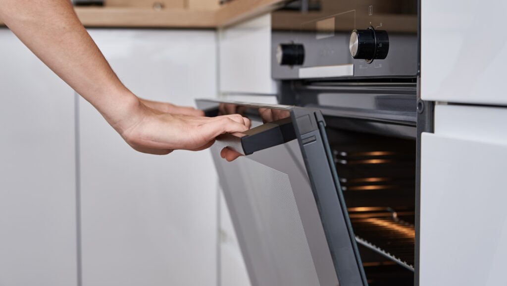 Woman,hand,open,electric,oven,door,with,handle.,homemade,cooking.