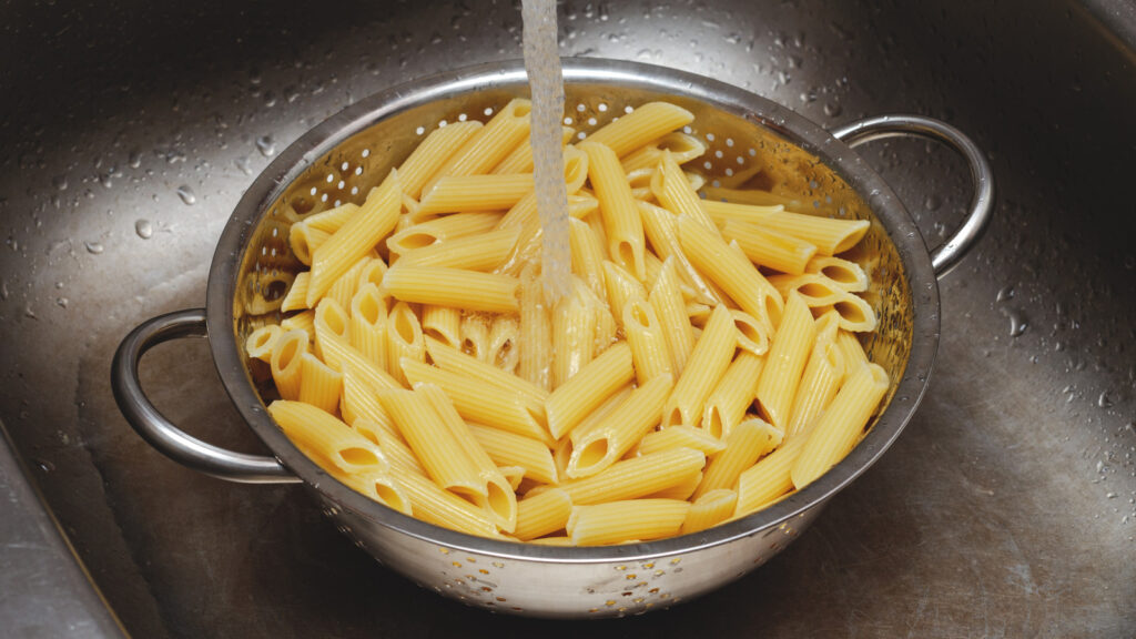 Washing,pasta,in,a,colander,with,water