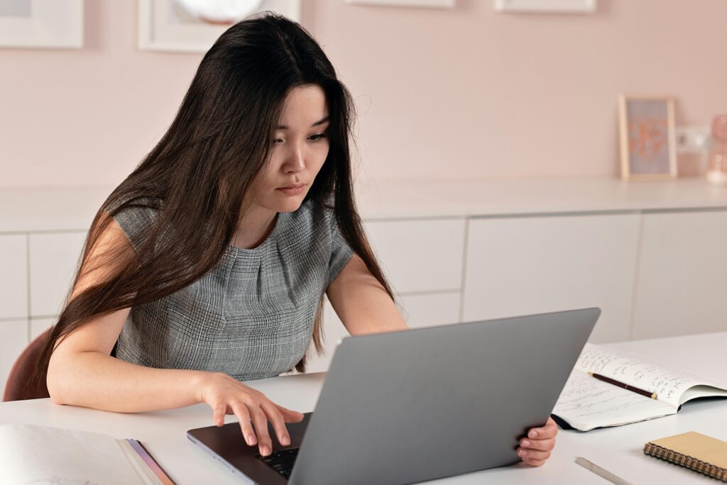 Young woman sits pensively in front of a laptop, scrolling through social media