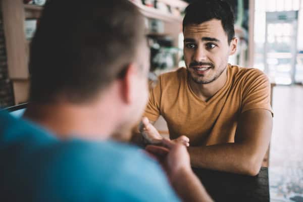 Serious male colleagues discussing information for startup project sitting at cafeteria table and feeling confused on fresh ideas, caucasian men brainstorming togetherness in coworking space