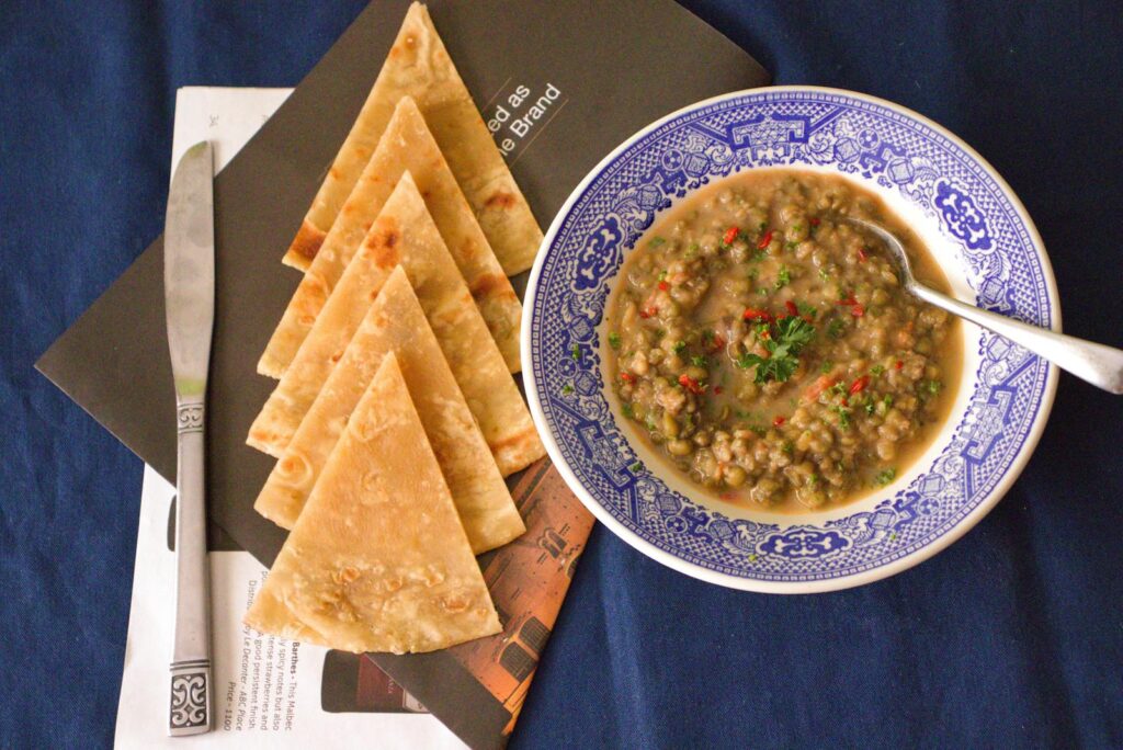 A flavorsome lentil soup paired with pita bread, captured in an appetizing overhead shot.