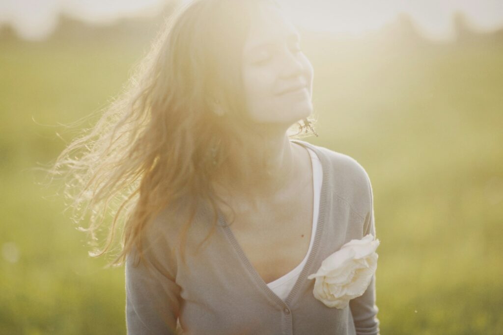 a woman standing in a field with a flower in her hand