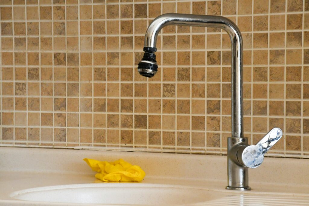 a kitchen sink with a faucet and a yellow sponge