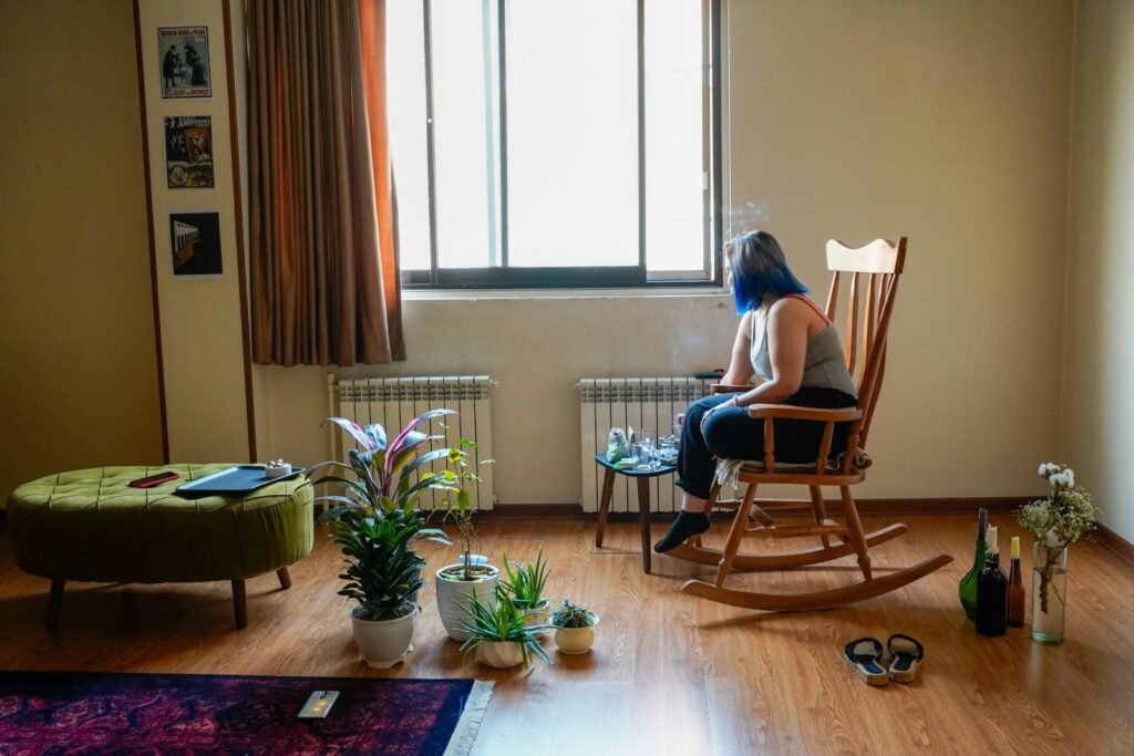 A woman sits alone in a sunlit room.