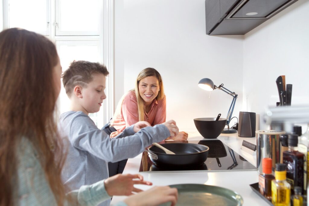 a woman and two children cooking in a kitchen