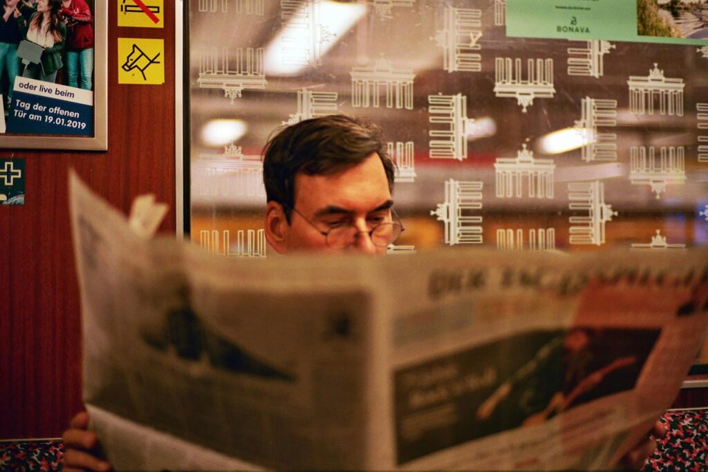 a man reading a newspaper in front of a window