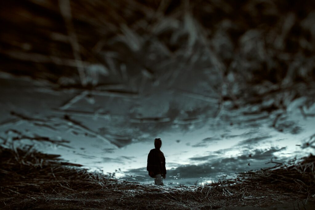 A man standing in the middle of a field under a cloudy sky