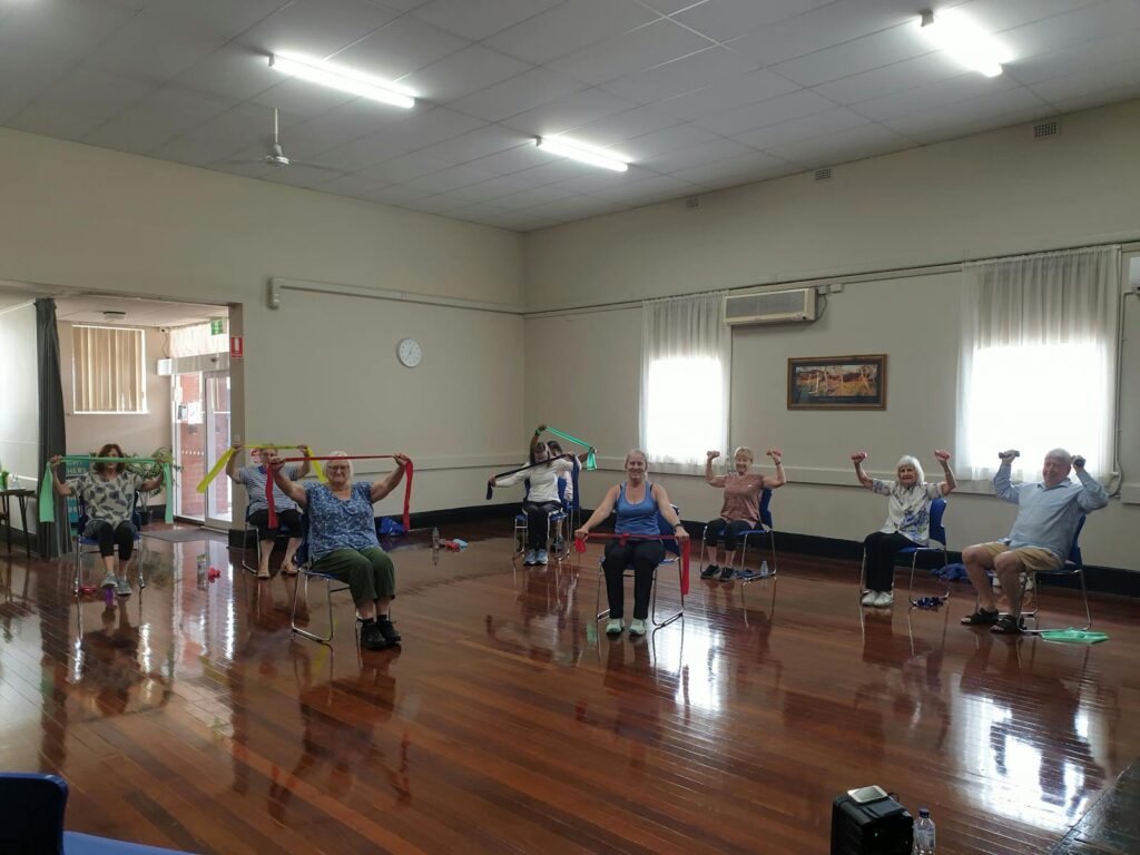 Active seniors engaging in a chair exercise class, promoting wellness and positive aging.