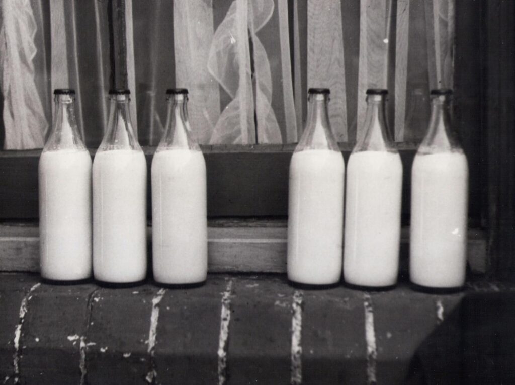 Vintage photo of glass milk bottles on a brick windowsill in monochrome.