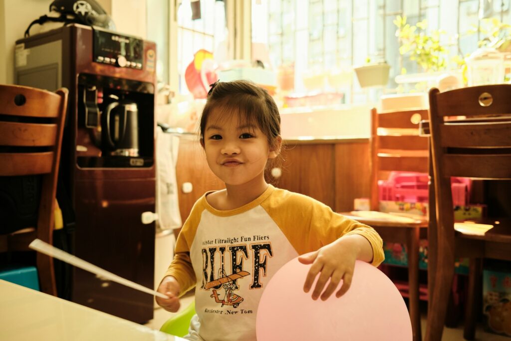 boy in yellow and white long sleeve shirt sitting on brown wooden chair