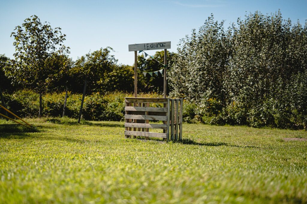 a wooden sign sitting on top of a lush green field