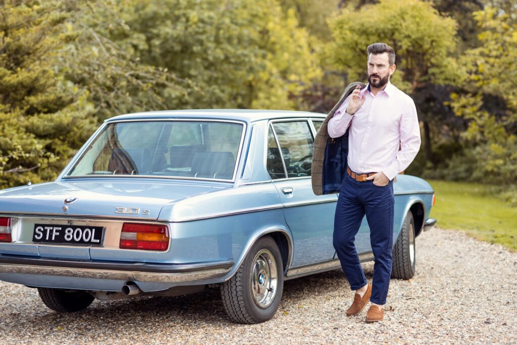 a man standing next to a blue car